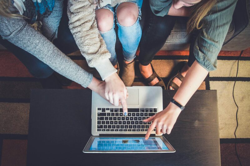 four students grouped around a laptop